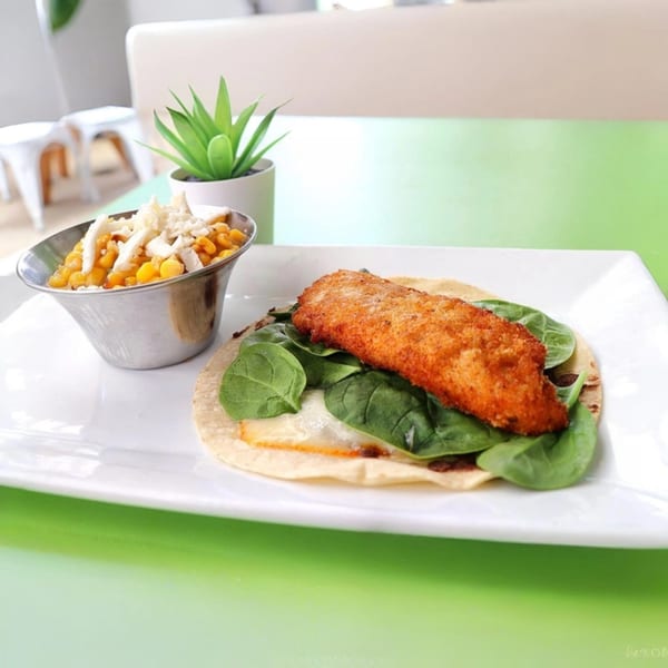 El Taquito's crispy fish taco with spinach and a side of corn and cheese.