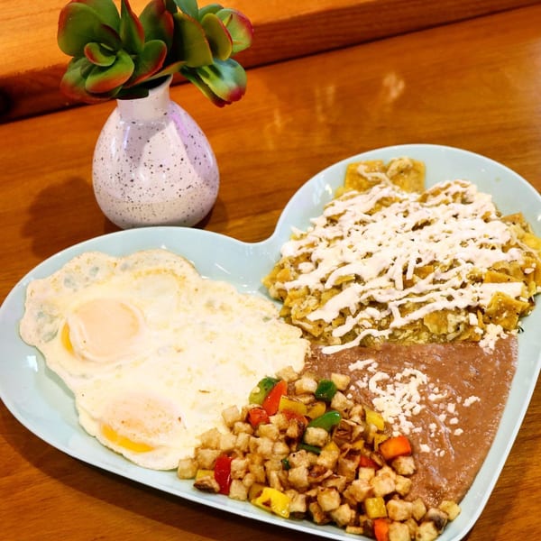 A heart-shaped plate of El Taquito's chilaquiles, fried eggs, refried beans, and breakfast potatoes.