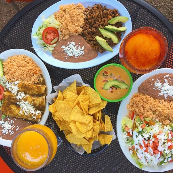 Overhead view of El Taquito's Mexican dishes, including tacos, enchiladas, rice, beans, chips, and drinks.